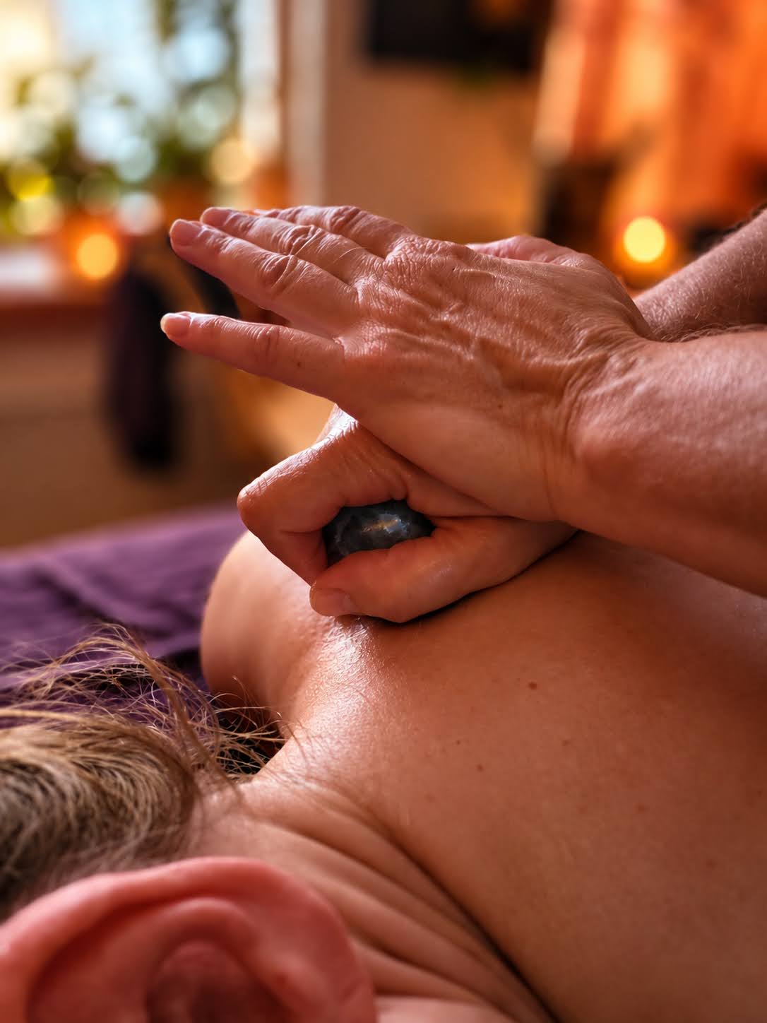 Massage van de schouder met een edelsteen in de hand